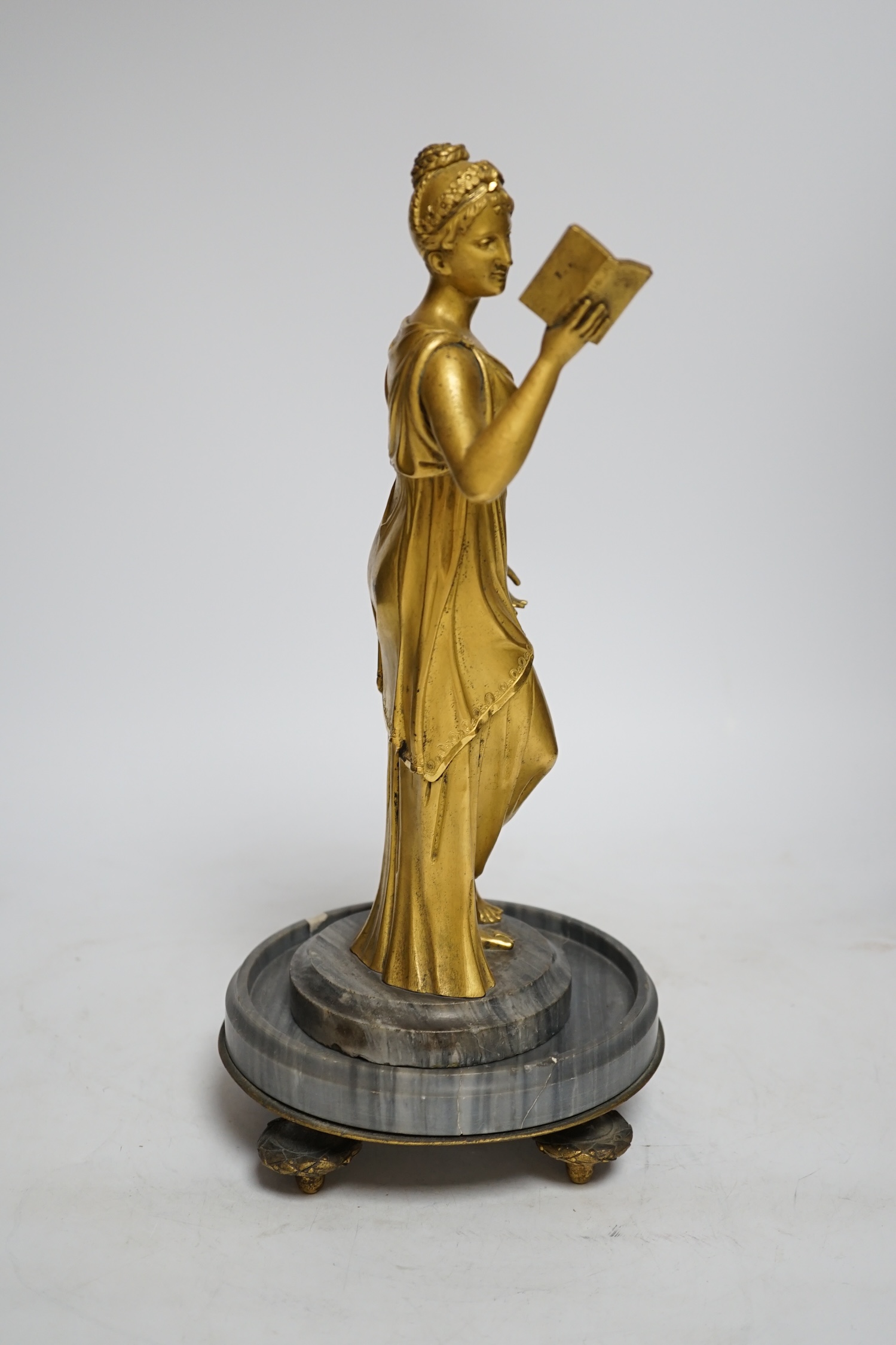 A 19th century French ormolu figure of a woman reading, on a two-piece grey marble base, 33cm high